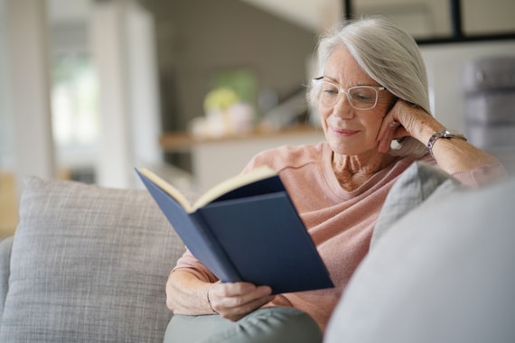 Senior woman reading on couch at home